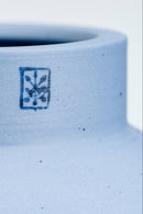 Close-up of a blue ceramic vase with a logo on a white background