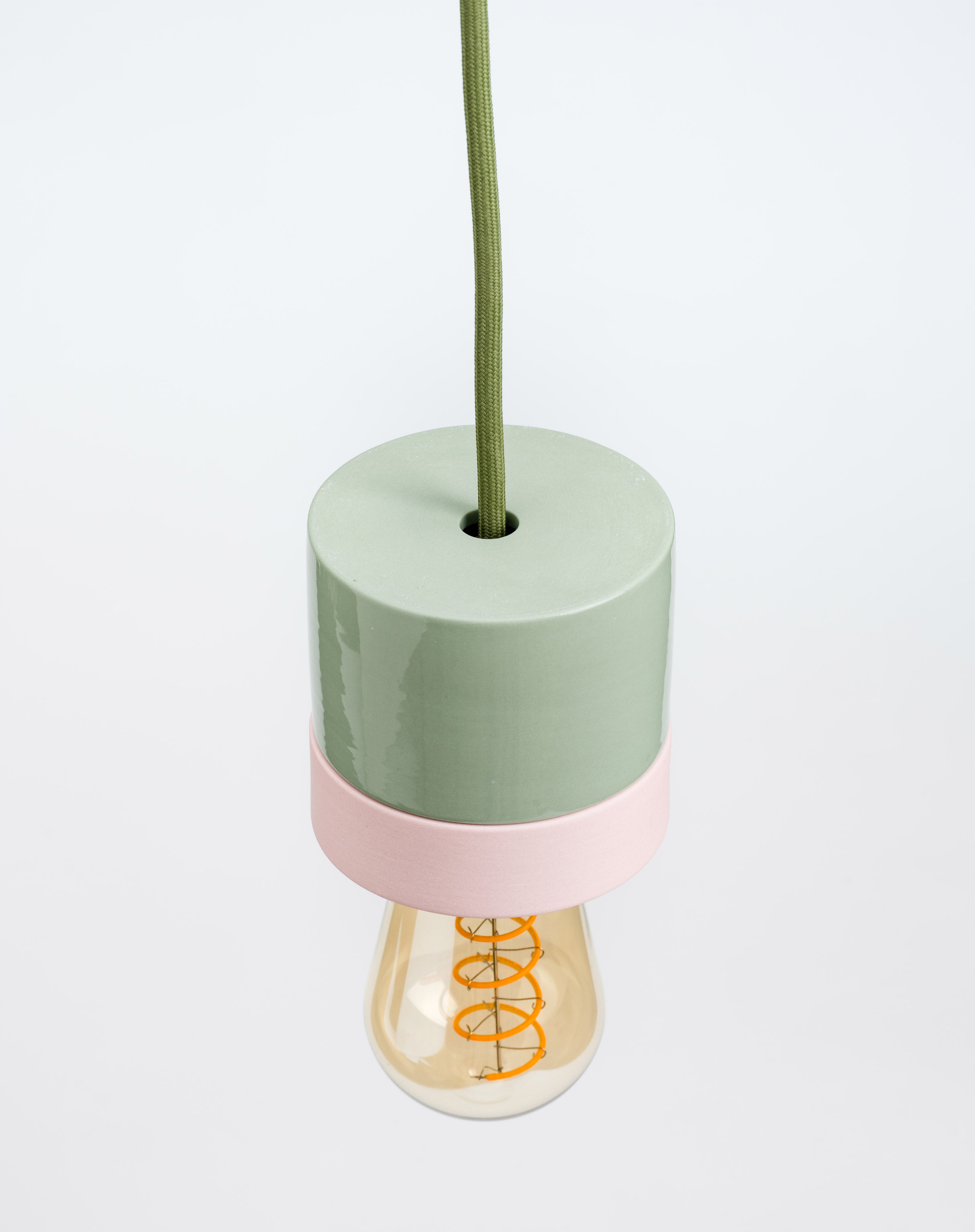 Decorative lamp with a green base and pink accent on a white background