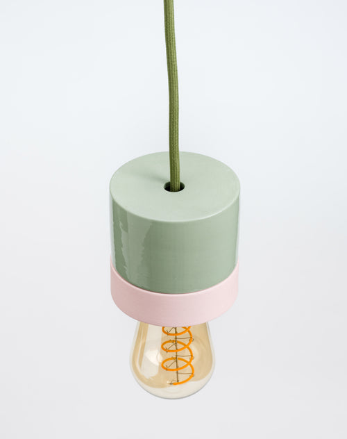 Decorative lamp with a green base and pink accent on a white background