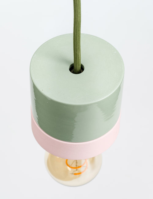Cylindrical lamp with green top and pink middle on a white background
