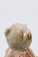 Small ceramic bear figurine on a metallic surface with a light gray background